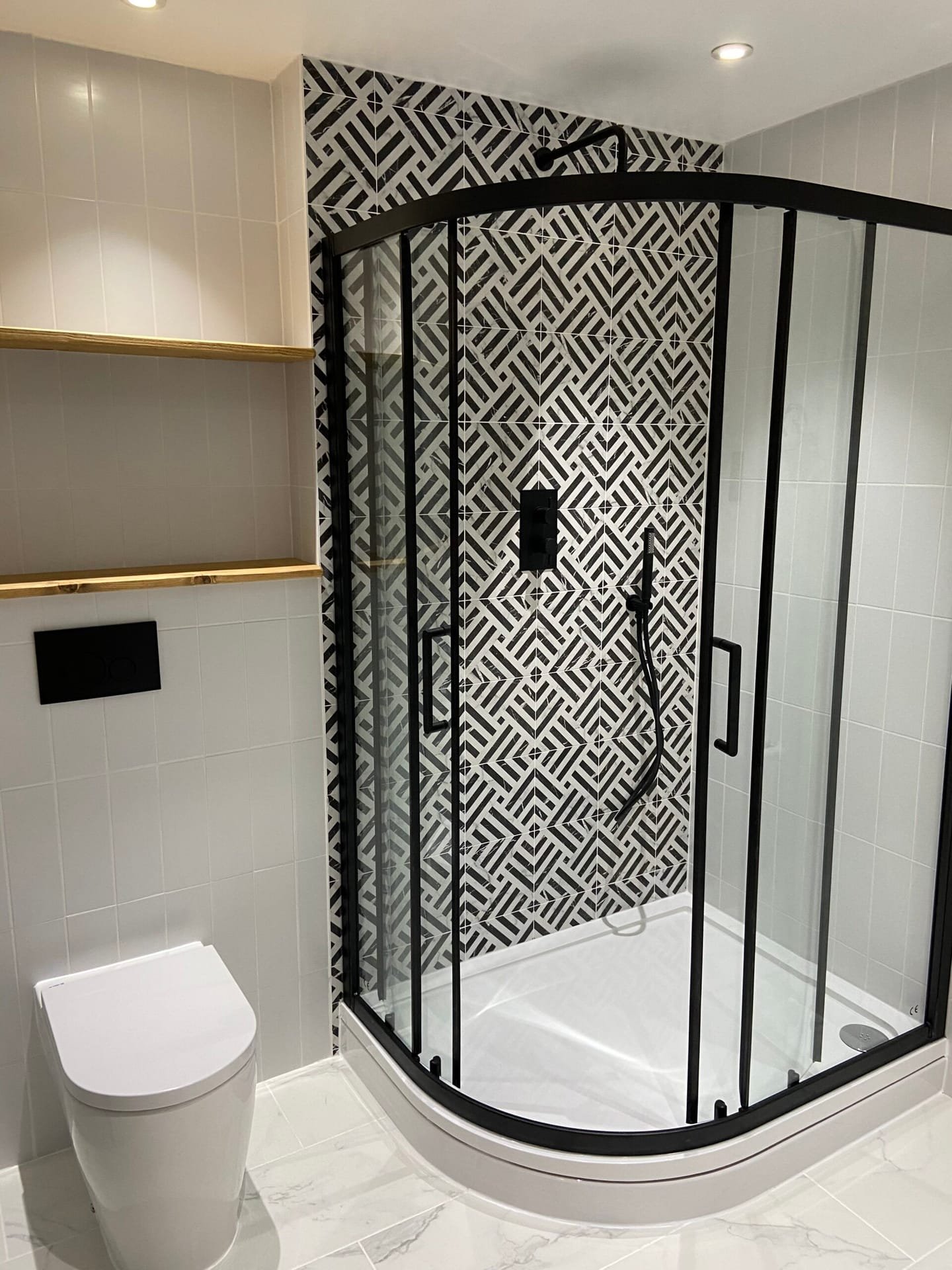 Contemporary corner shower with black frame, geometric tiles with niches, and white shower tray in a Weybridge home.