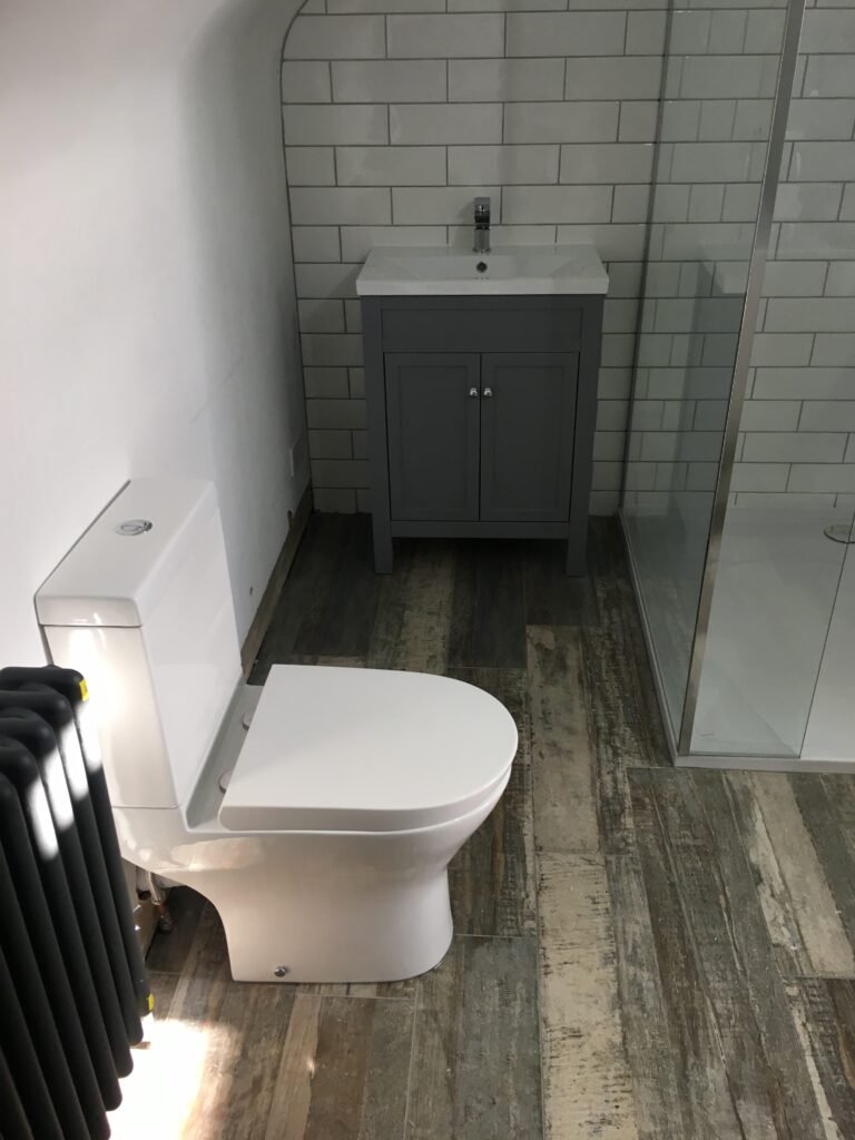 Modern bathroom with close-coupled toilet, grey vanity unit, and glass shower enclosure