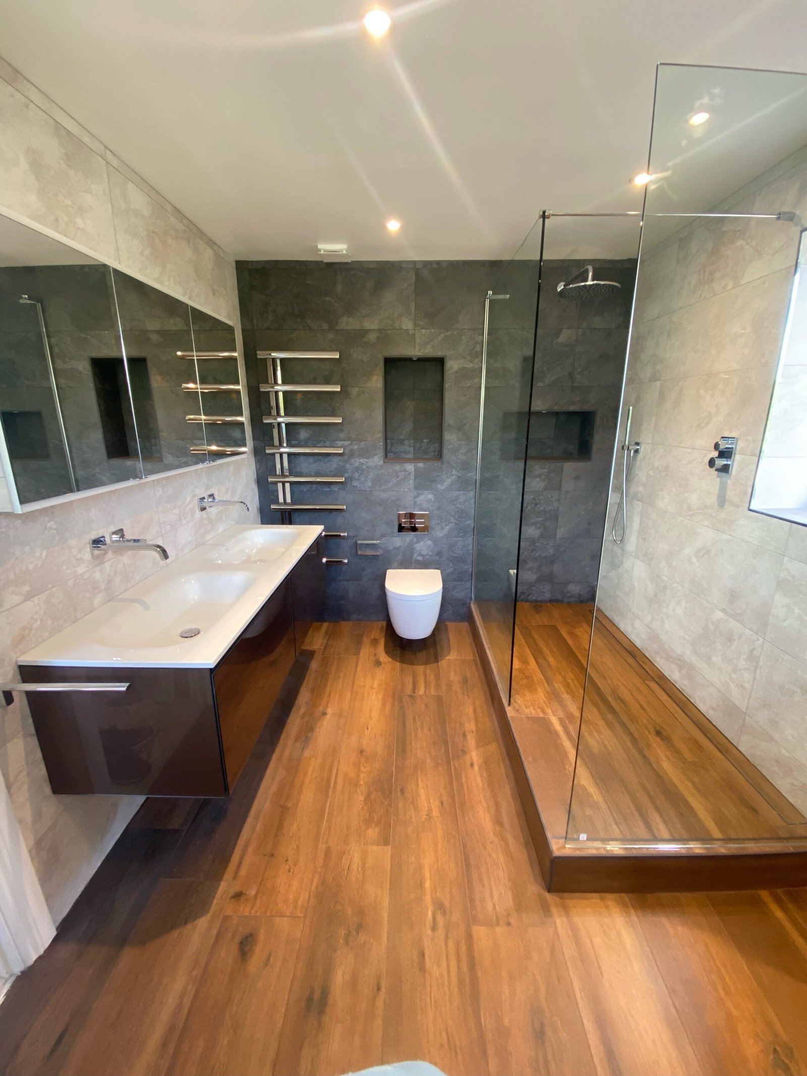 Luxury bathroom installation in Weybridge with walk-in shower, wall-hung vanity, and wood flooring by Summer Plumbing